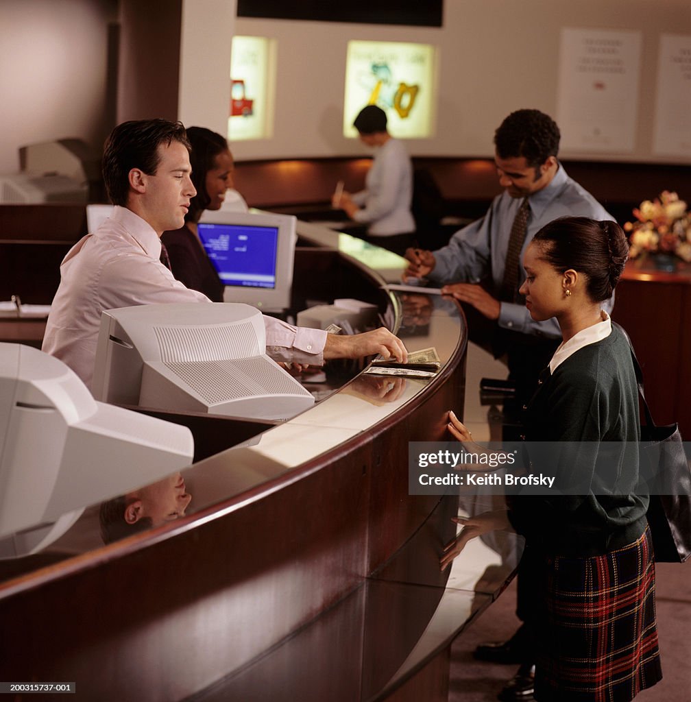 Teller giving money to woman in bank, elevated view