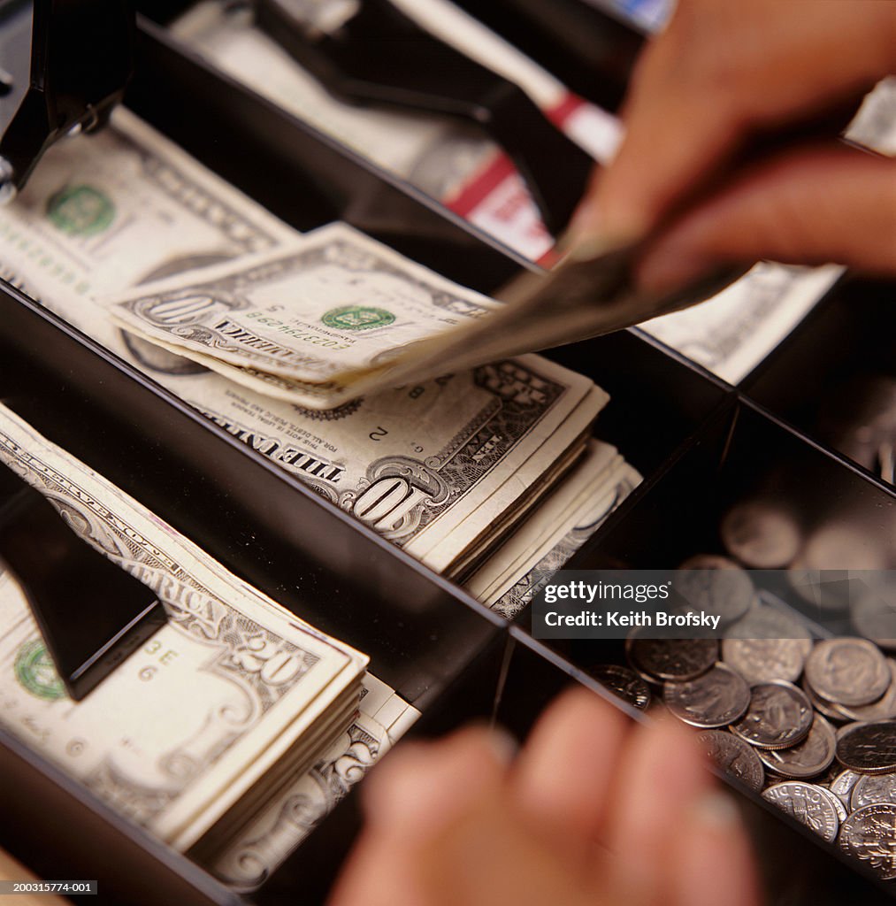 Person taking money from cash register, close-up