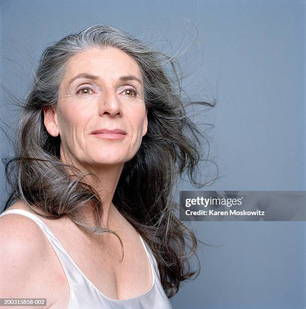 mature woman with blowing hair, low angle view - low confidence stock pictures, royalty-free photos & images