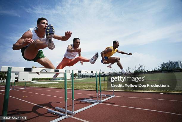three athletes jumping hurdle - hürdenlauf stock-fotos und bilder