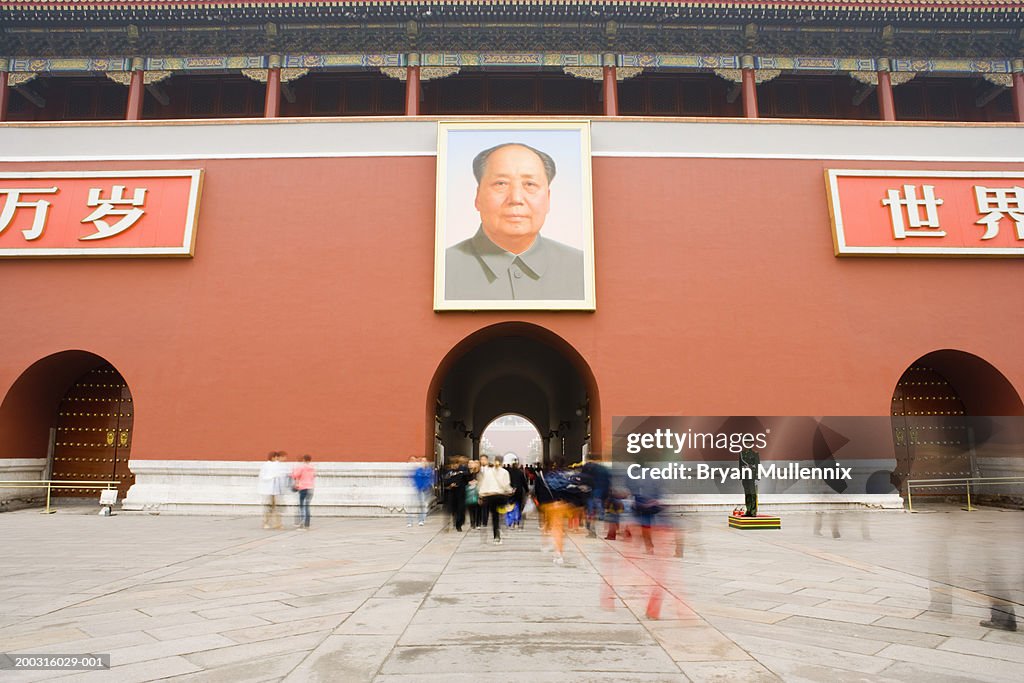 People walking under portrait of Chairman Mao at Tiananmen Gate