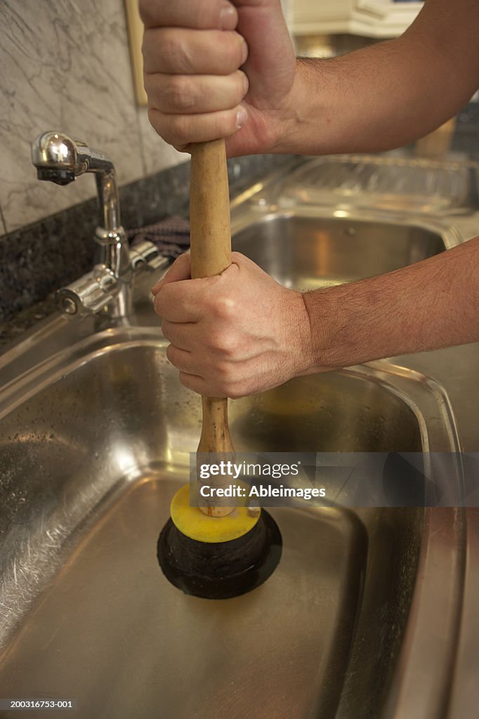 Man Using Plunger In Kitchen Sink Closeup High-Res Stock Photo - Getty  Images