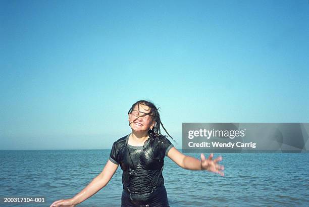 girl (10-12) by sea with wet hair across face, eyes closed, smiling - wet girl stock-fotos und bilder