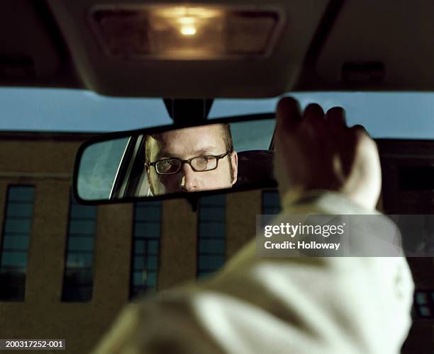 man sitting in car adjusting rear view mirror, close-up - car rear view mirror stock pictures, royalty-free photos & images