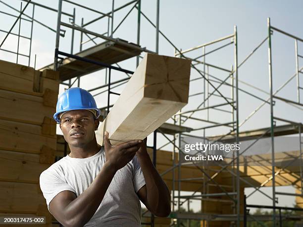 construction worker holding wood at site looking away - carry foundation stock-fotos und bilder