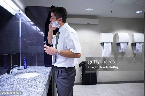 businessman shaving at sink in public toilets - rasieren stock-fotos und bilder