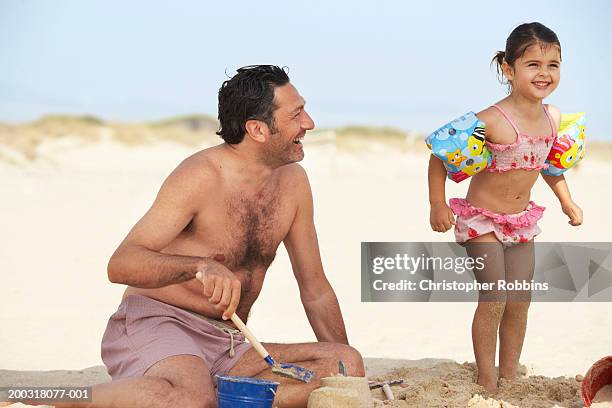 girl (2-4) on beach wearing arm bands, standing next to father - female hairy chest photos et images de collection