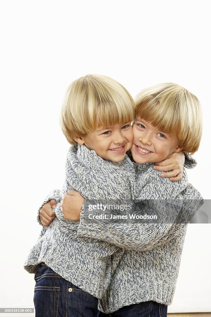 Twin boys (3-5) embracing, smiling, portrait