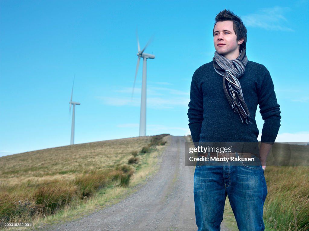 Young man standing on track, wind turbines in background