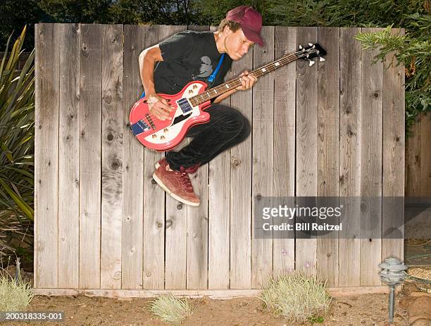 teenage boy (13-15) playing bass guitar, jumping in midair, side view - bass guitar stock pictures, royalty-free photos & images