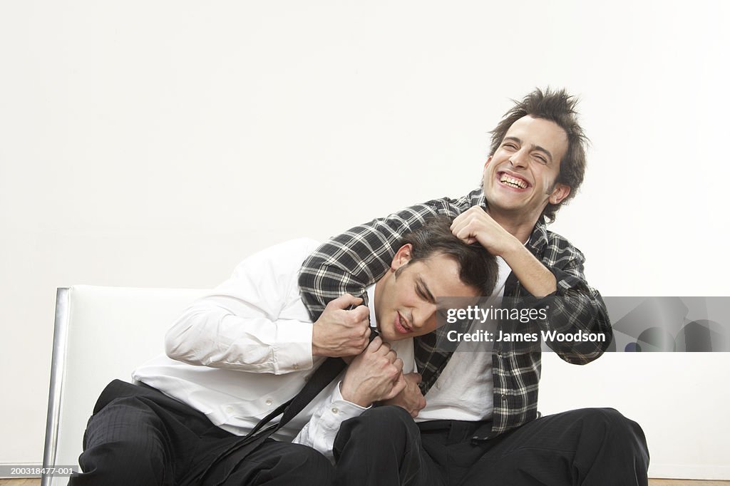 Young man holding twin brother in headlock, smiling