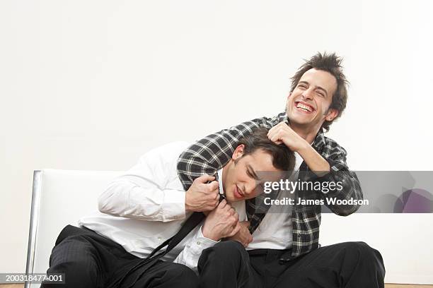 young man holding twin brother in headlock, smiling - adult siblings stock pictures, royalty-free photos & images