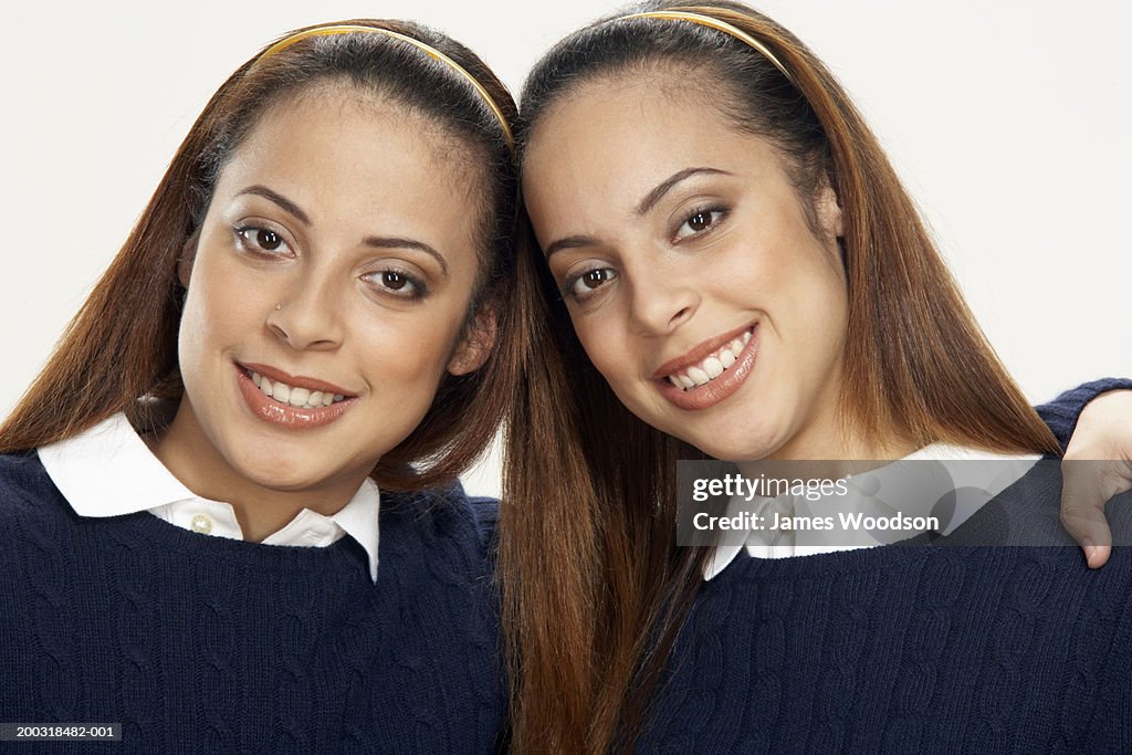 Young female twins head to head, smiling, portrait, close-up