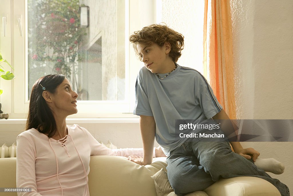 Mother and son (10-12) on sofa, looking at each other