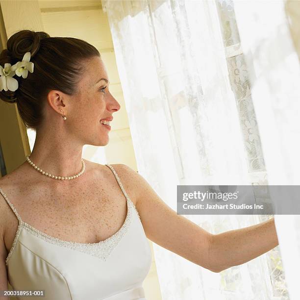 young bride pulling back curtain, looking out window - pulling back curtain stock pictures, royalty-free photos & images