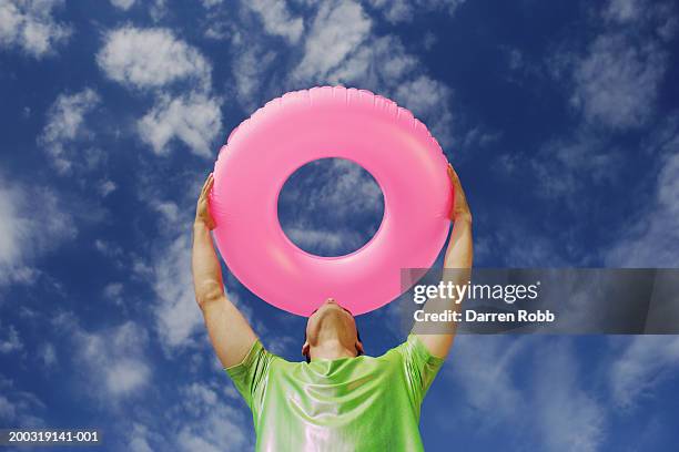 man holding up inflatable plastic ring - pink tube stock pictures, royalty-free photos & images