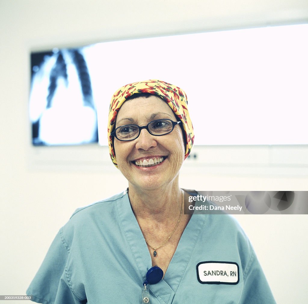 Senior female nurse smiling, X-ray on lightbox in background