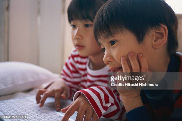 children (4-7) using laptop on bed - command sisters photos et images de collection