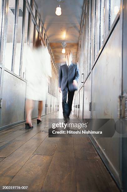 man and woman walking in corridor, low angle view, blurred motion - vorbeigehen stock-fotos und bilder