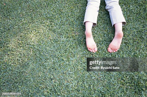 woman lying on grass, low section - woman lying on stomach with feet up foto e immagini stock