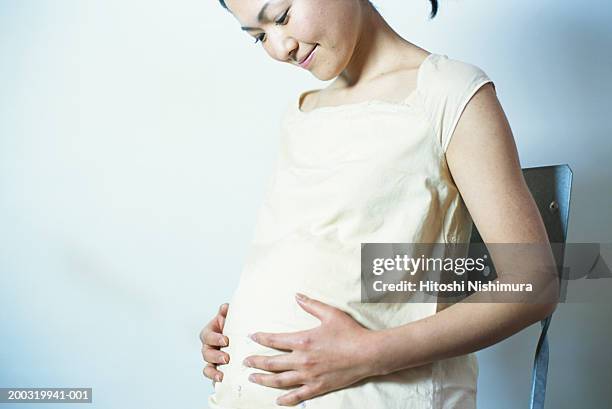 pregnant woman looking at stomach, smiling - dierenfoetus stockfoto's en -beelden