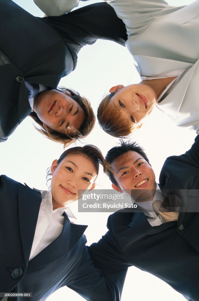 Businesspeople in scrum, smiling, view from below