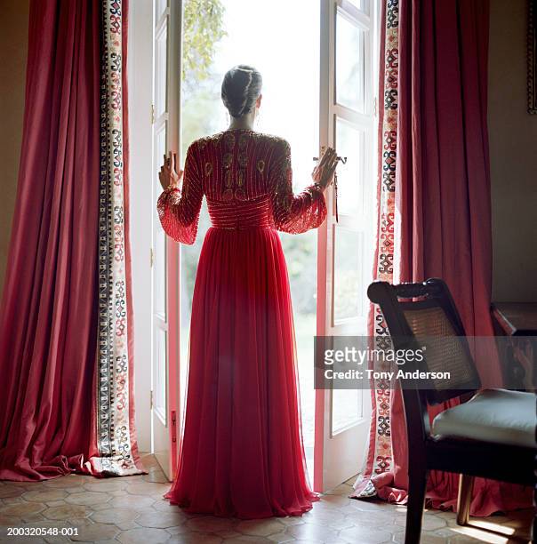 woman standing in open doorway leading to garden, rear view - french doors stock pictures, royalty-free photos & images