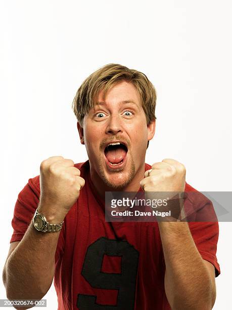 man in t-shirt clenching fists, cheering, portrait, close-up - man cheering foto e immagini stock