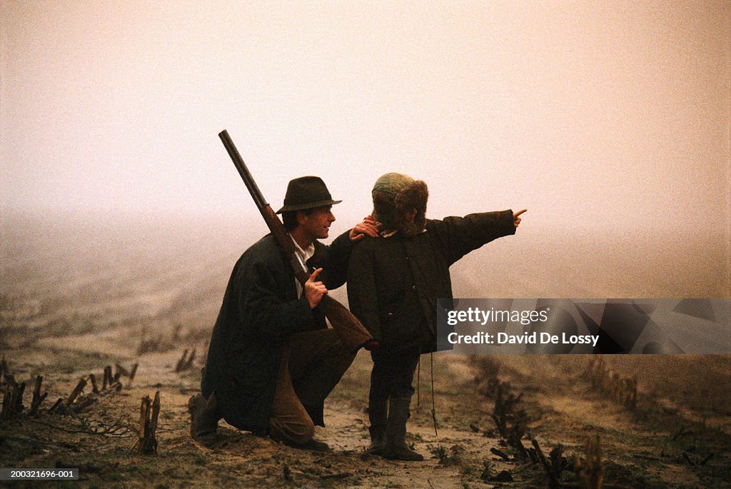 Father with son (4-5) standing outdoors, boy pointing