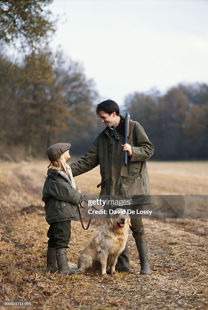 Father and daughter (4-7) with dog standing in forest