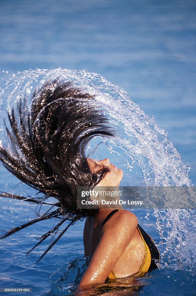Young woman tossing wet hair back in sea, side view
