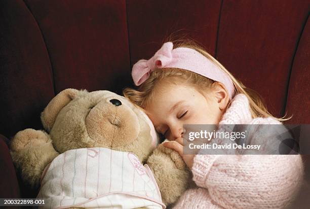 girl (6-7) sleeping with teddy bear on sofa, eyes closed - david de lossy sleep stock pictures, royalty-free photos & images