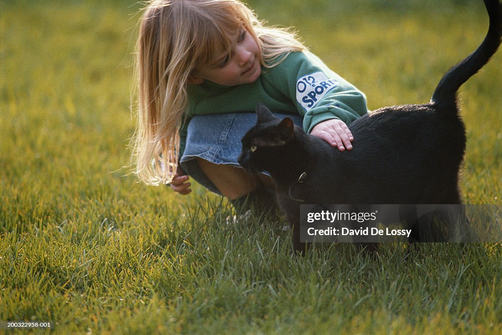 Girl (2-3) playing with cat in garden
