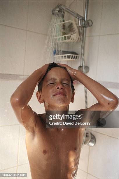 boy (8-9) standing under shower in bathroom - kids taking a shower stockfoto's en -beelden