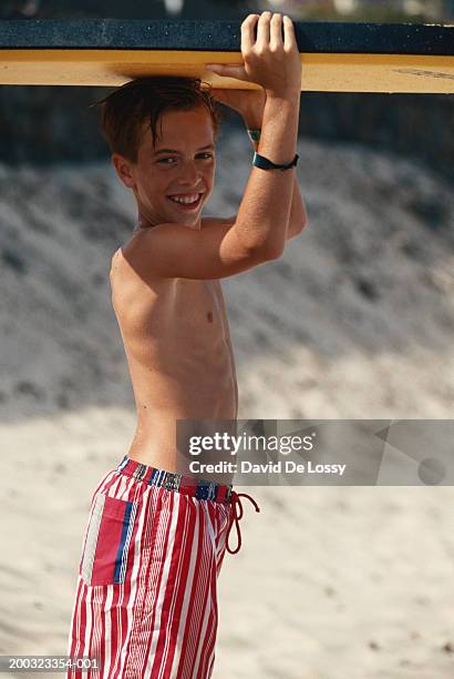 Boy Carrying Surfboard On Beach Smiling High-Res Stock Photo