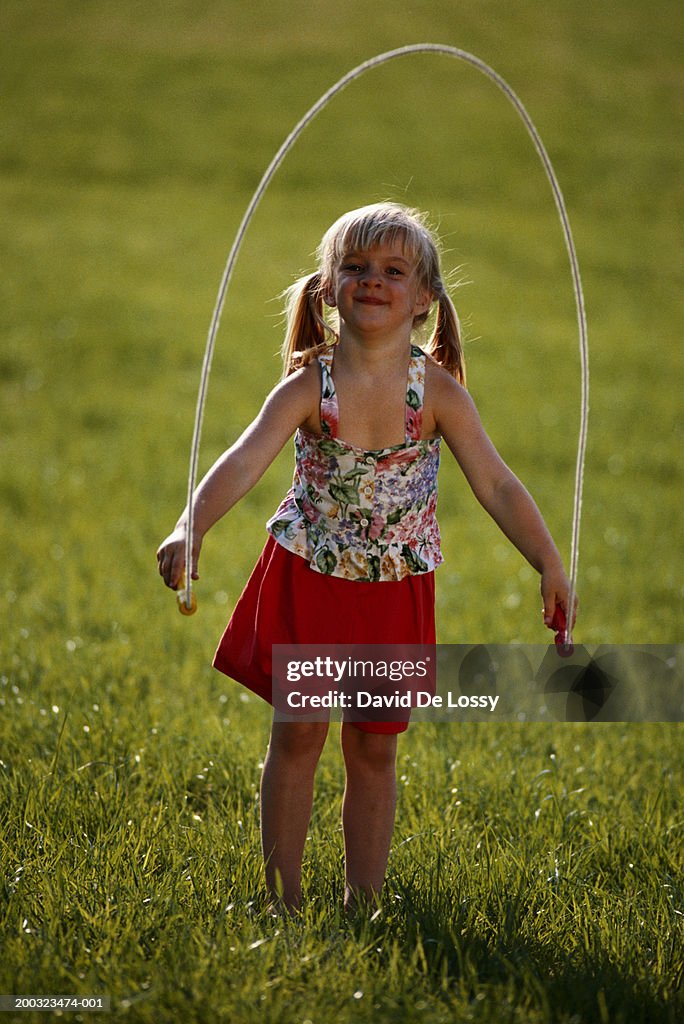 Girl (3-5) holding skipping rope in garden