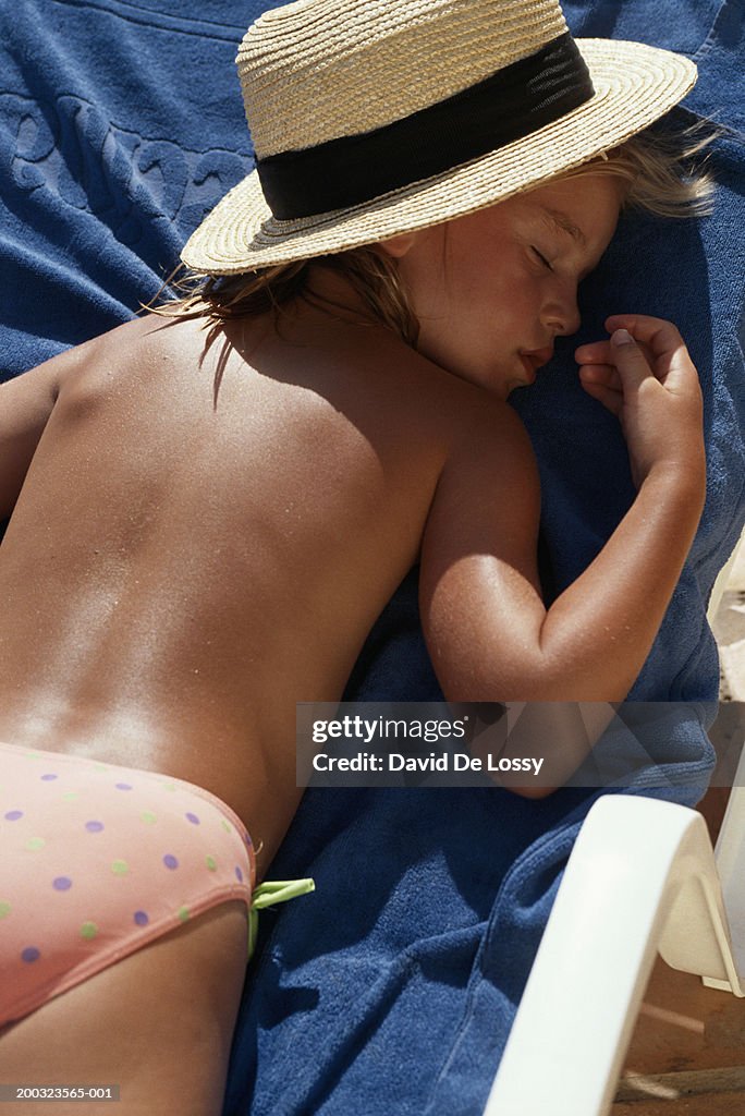 Girl (6-7) lying on beach, eyes closed, elevated view