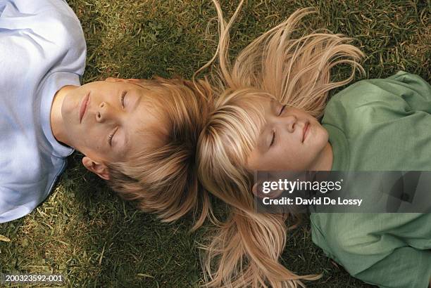 girl and boy (6-9) lying on grass, elevated view, eyes closed - david de lossy sleep stock pictures, royalty-free photos & images