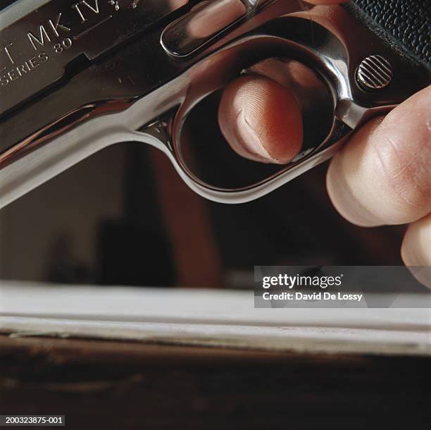 hand holding gun, close-up, low angle view - feuerwaffen abzug stock-fotos und bilder