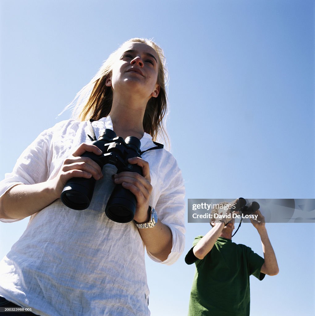 Couple outdoors, man using binoculars, low angle view