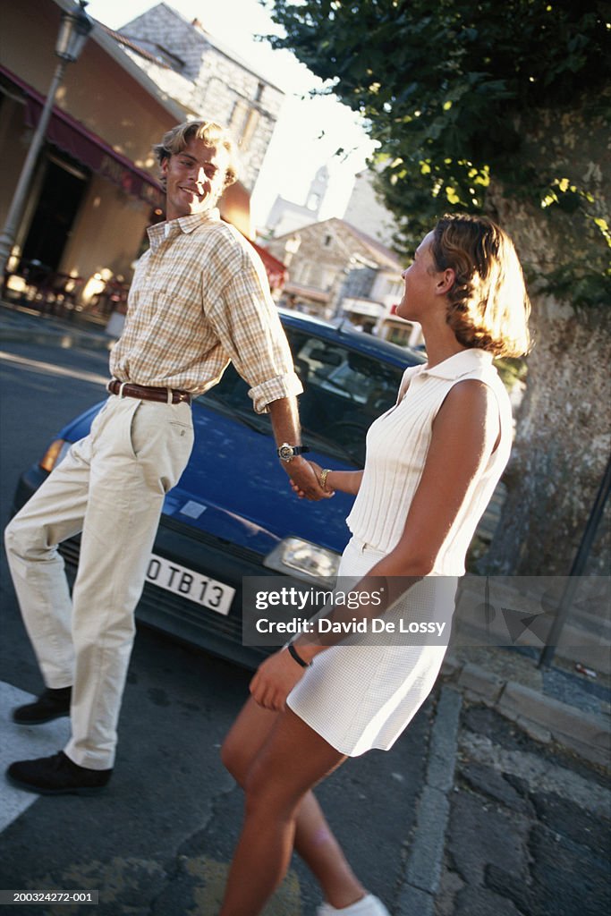 Young couple walking on street, holding hands