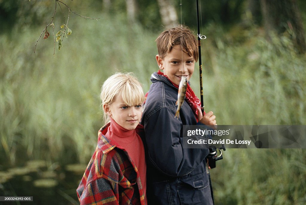 Boy and girl (6-8) with fish in fishing rod