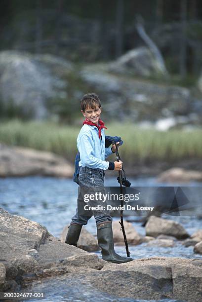 boy (8-9) walking on rocks holding binoculars, smiling - boy river looking at camera stock pictures, royalty-free photos & images