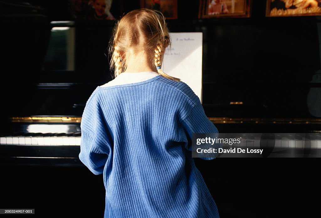 Girl playing piano, rear view