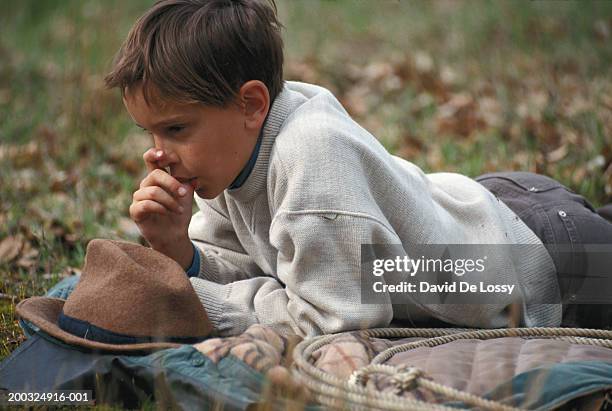 boy (6-9) lying on grass, sucking thumb, ground view - thumb sucking stock pictures, royalty-free photos & images