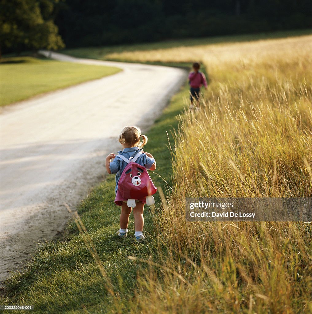 Girl (2-4) walking by road side with satchel