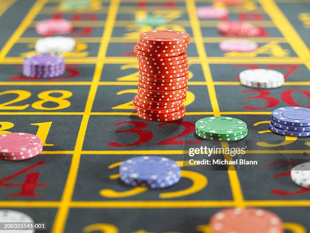 stack of red gambling chips over two numbers on roulette table - roulette stock-fotos und bilder