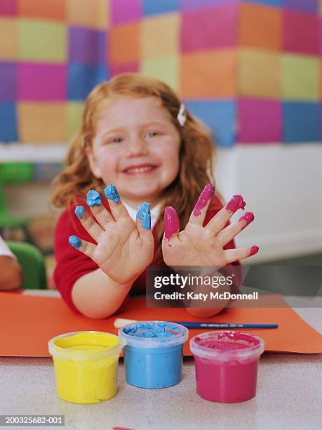 schoolgirl (4-6) holding up paint covered fingers, smiling, portrait - 4 girls finger painting bildbanksfoton och bilder