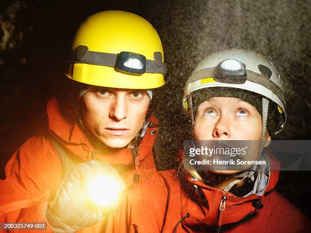 man and woman wearing safety helmets, man holding torch - spelunking stockfoto's en -beelden