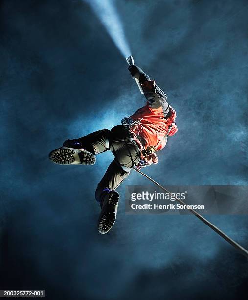 man abseiling in cave, holding torch, view from below - pothole stock pictures, royalty-free photos & images